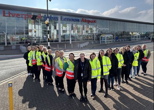 A group of women workers, most of them in high-vis jackets, outside the airport terminal